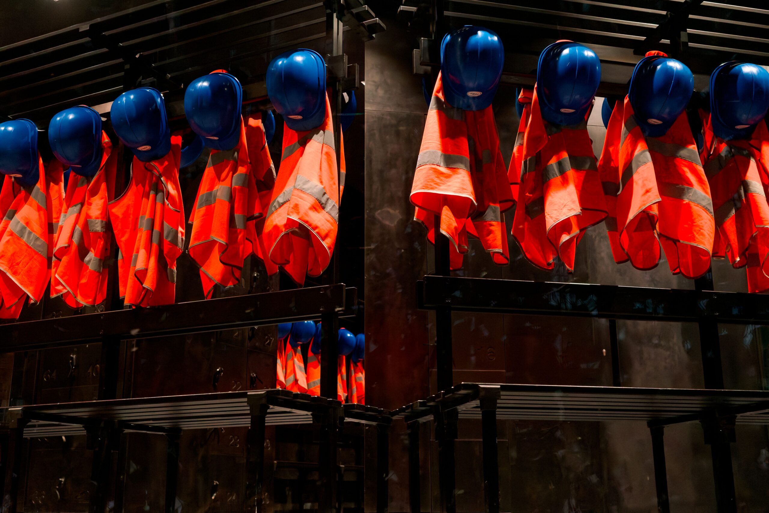 Hard hats and high-visibility vests in worker lockers.